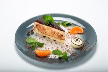 The cake on the plate is decorated with tangerines and chocolate