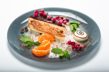 The cake on the plate is decorated with tangerines and chocolate