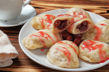 A white plate with sweet boiled dough vareniki with cherry. Ukrainian national dish. Close-up view.