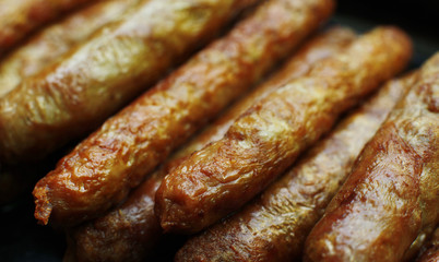 Barbecued meat sausages (bratwurst) close up. Grilled delicious sausages macro shoot.