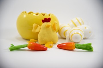 Yellow Easter egg and chicken with small decorative eggs and carrots