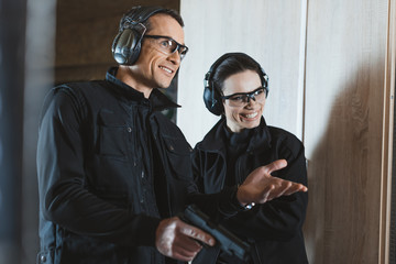 smiling shooting instructor and customer in shooting gallery