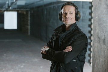 smiling handsome man with crossed arms looking at camera in shooting range © LIGHTFIELD STUDIOS