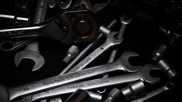 The tool is made of steel on the table in the workshop. The master selects the instrument with his hand. A beautiful chrome set of tools.