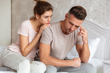 Lovely couple sitting on bed while woman calm down boyfriend