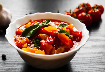 Delicious letcho with fresh vegetables in bowl on dark wooden background