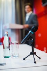 Close-up of a Microphone on a Table with Speaker and Podium on