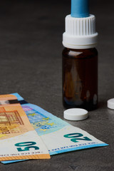 Euro Geldscheine und Medizinflasche mit Tabletten, Fokus auf den Geldscheinen, vertikal
