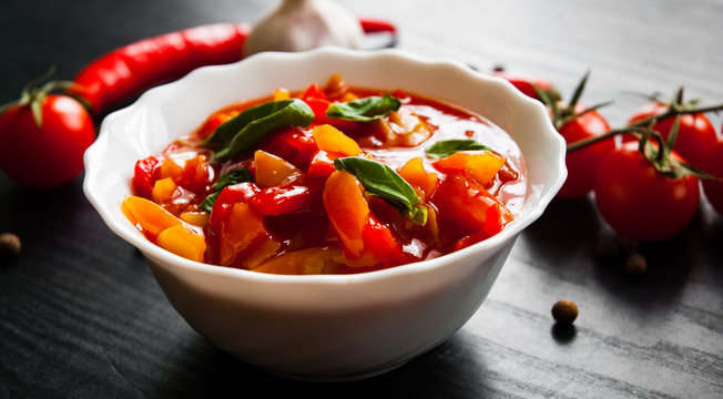 Delicious letcho with fresh vegetables in bowl on dark wooden background