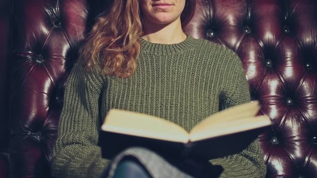 Young woman on sofa reading book