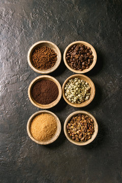 Variety of grounded, instant coffee, different coffee beans, brown sugar in wooden bowls in row over dark texture background. Top view, space © Natasha Breen