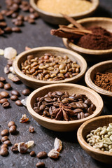 Variety of grounded, instant coffee, different coffee beans, brown sugar, spices in wooden bowls over dark texture background. Close up