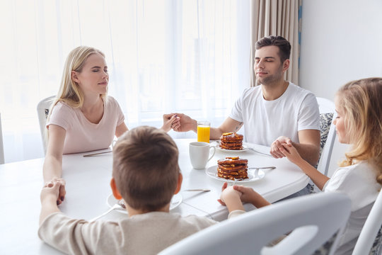 christian family praying before breakfast and holding hands - Powered by Adobe