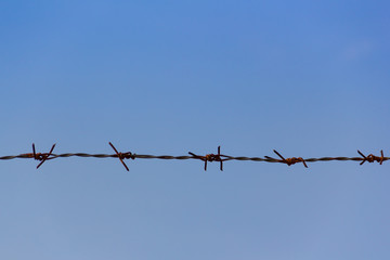 Rusty barb wire and blue sky background
