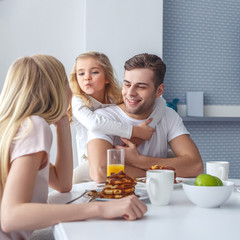Obraz na płótnie Canvas young happy family having breakfast and having fun on weekend morning