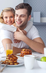 daughter embracing her father from behind while he having breakfast