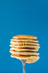 Photo sur Plexiglas Dessert Stack of pancakes with honey decorated sweet cherry pinned on a fork on blue background