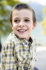 portrait of 9 year old boy smiling with colorful shirt sitting on a wall