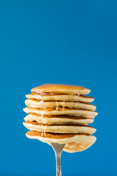 Naklejki Stack of pancakes with honey decorated sweet cherry pinned on a fork on blue background