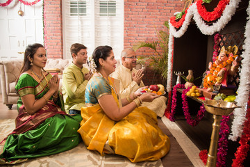 Indian  family performing Ganesh puja or Ganpati Puja in Ganesh Utsav, or holding ganesh idol over...
