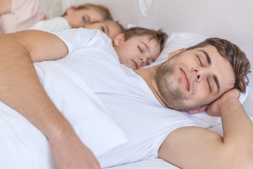 Fototapeta na wymiar young family sleeping together in bed