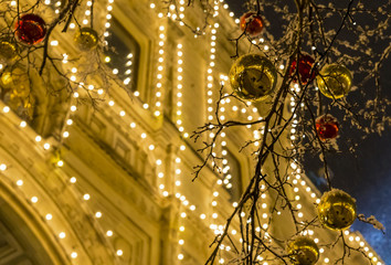 golden red ball bright decoration on a festive winter evening against a yellow building background decorated with a glowing garland