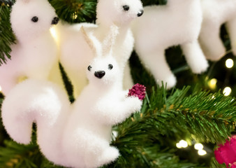 toy christmas white fluffy squirrel with red cone and deer close-up sits on a green spruce branch, decorating the foundation of a christmas and new year