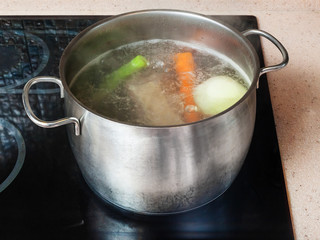 simmering meat stock in stockpot on ceramic cooker