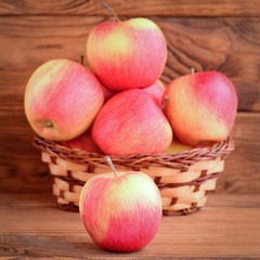 Small red apples on a wooden table and in a basket. Brown wooden background. Apples photo. Healthy natural dessert. Good source of pectin and iron