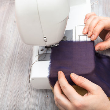 designer sews strips of fabrics for patchwork