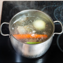 boiling meat broth in stockpot on ceramic cooker