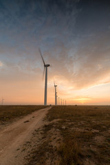 Wind turbines against red, blue and orange sunrise