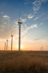 Fototapeta na wymiar Wind turbines against red, blue and orange sunrise