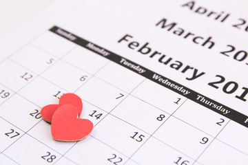 Calendar page and red hearts paper on February 14 of Valentines day.