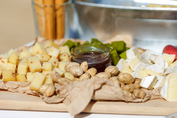 Salty and cheese bar of several kinds of cheese, grapes, olives, jamon, honey, nuts and snacks decorated on vintage wooden table. Wedding or other holiday party outdoors, picnic