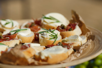 Salty and cheese bar of several kinds of cheese, grapes, olives, jamon, honey, nuts and snacks decorated on vintage wooden table. Wedding or other holiday party outdoors, picnic