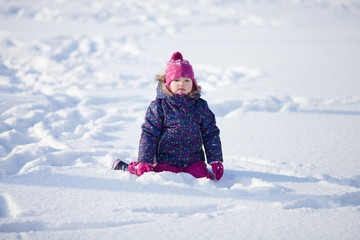 Little cute toddler girl outdoors on a sunny winter day.