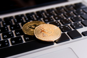 Golden bitcoin coins on keyboard laptop with trading chart background