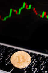 Golden bitcoin coins on keyboard laptop with trading chart background