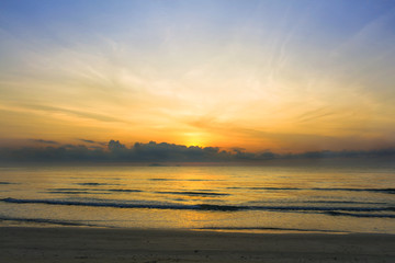 Fototapeta premium Sunrise over the tropical seacoast beach. The wave of seawater up the beach and waves slowly splashing on the sand.