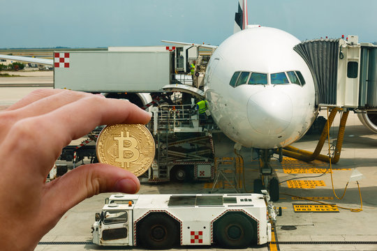 Hand holding golden bitcoin virtual money airplane airport