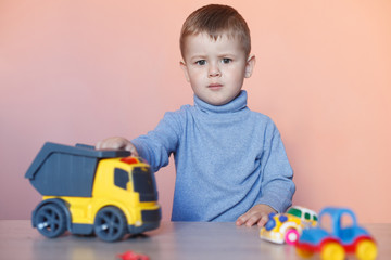 A cute little boy playing with model car collection. Toy mess in child room. Educational games for kids.