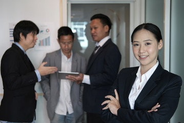 asian businesswoman smiling at camera while colleagues have meeting at office. businessman working with co worker team