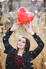 attractive young girl with a balloon in the shape of a heart in hands. Valentine's Day