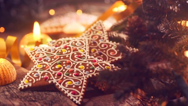 Christmas scene. Gingerbread cookies on wooden table decorated with garland and burning candles. 4K UHD video footage. 3840X2160