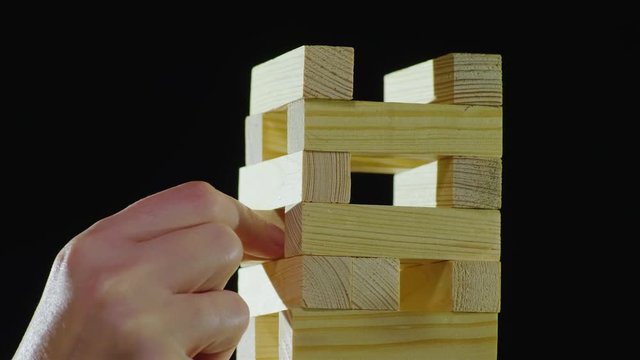 The hand pulls a wooden block from the tower. Playing in Djanga. Board games concept