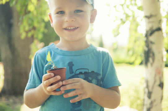 The Child Is Holding A Flower Pot With A Small Plant