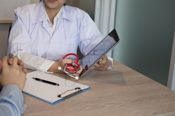 doctor showing test result on tablet to patient at hospital. physician talk & give advice to man about his health at medical office