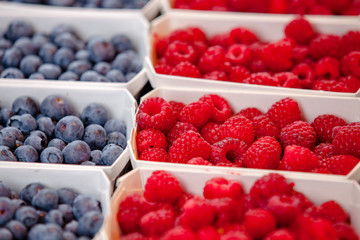 Fresh raspberries and blueberries in white containers