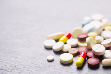 Colorful different capsules and pills on gray background